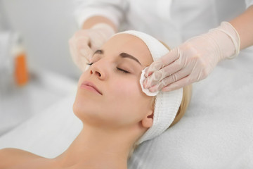 Fototapeta na wymiar Cosmetologist cleaning woman's face
