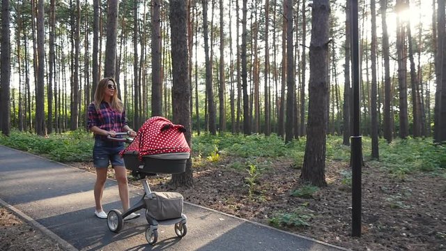 Mother with baby in buggy walking in park