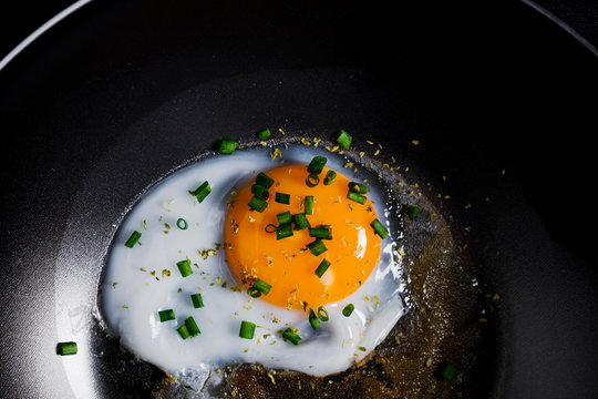 Fried eggs with onion in black pan
