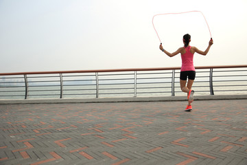 young fitness woman jumping rope on seaside