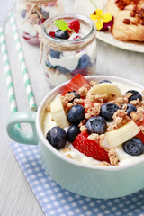 Bowl of yogurt with muesli and fresh fruits: strawberries, blueb