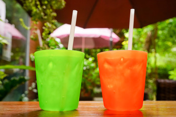 two plastic glass with straw on wooden background