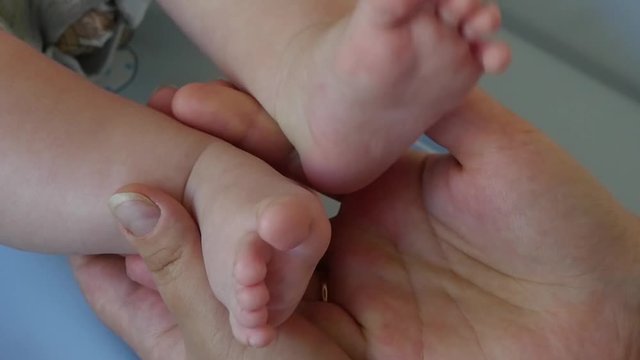 Slow motion shot of a newborn baby feet on female hands