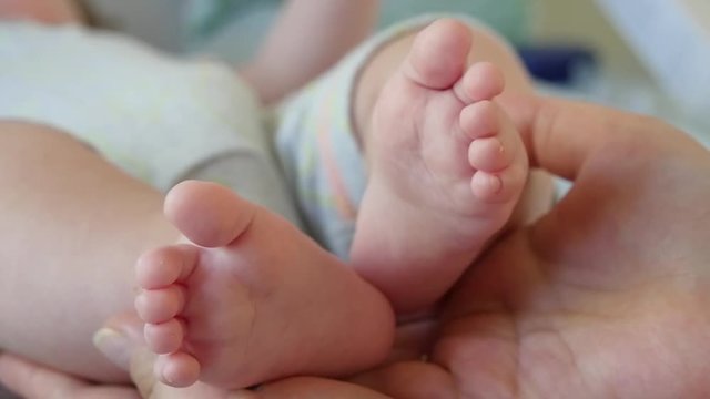 Slow motion shot of a foot the baby in adult hands