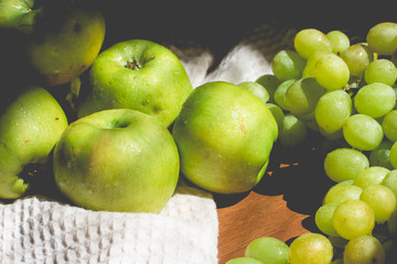 Bunch of grapes with apples on wooden tray on a black background, horizontal, soft focus