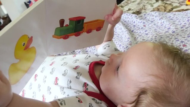 Slow motion shot of a portrait of cute baby reading a picture book