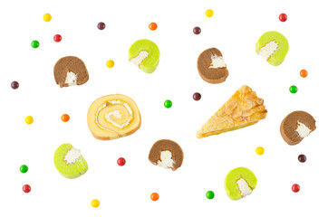 Flat lay image of Swiss roll, corn pie, chocolate and pandan cake rolls with sweet multi-color candies isolated on white background for happy party time celebration or fun and special occasion