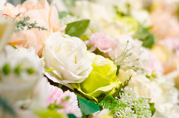 Background of beautiful fabric made white, green, peach, and pink roses and leaves. Selective focus of nature background under sunlight for celebration, decoration, exhibition or special occasion