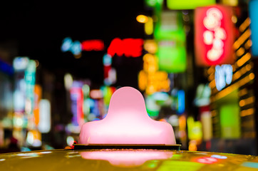 Close-up bright pink light box on the roof of yellow taxi cab parking at entertainment or shopping...