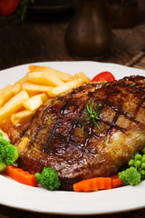 Grilled beef steak served with French fries and vegetables on a