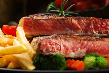 Grilled beef steak served with French fries and vegetables on a
