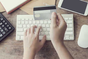 woman using computer to online shopping and pay by credit card, Low light, selective focus on hand, can be used for e-commerce, business, technology and internet concept, Vintage tone filter
