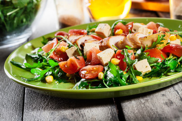 Fresh salad with chicken breast, arugula and tomato
