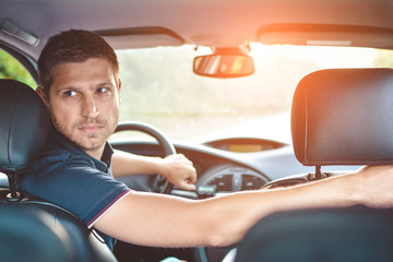Handsome man driver looking back and parking car