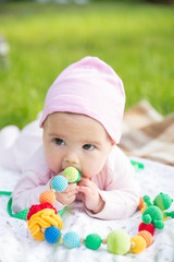 Baby girl crawling on the grass with sling beads