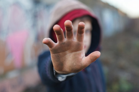 dramatic portrait of a little homeless boy, dirty hand