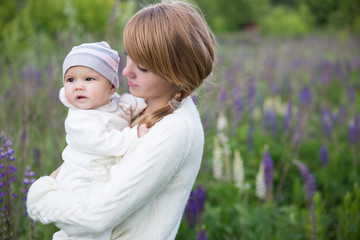 Young mother with baby at meadow lupins flowers