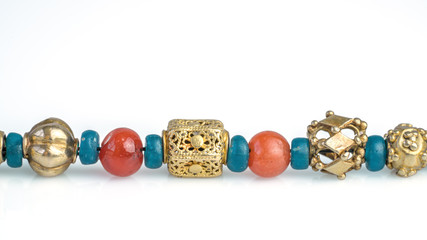 Close up ancient rare craved gold beads separated with turquoise glass beads and carnelian beads in...