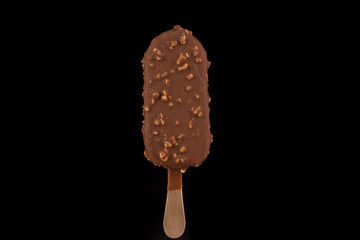 Vanilla ice cream covered with chocolate and peanuts on black background