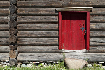 Beautiful old red door on the wooden wall of the old house. Excellent background.