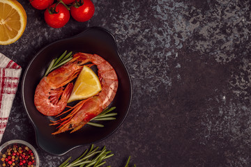Grilled shrimps with lemon and rosemary on frying pan.