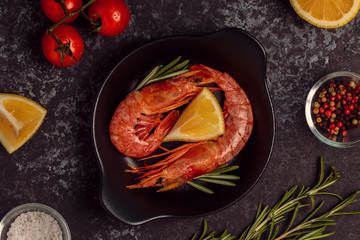 Grilled shrimps with lemon and rosemary on frying pan.