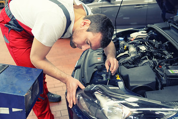 KFZ-Mechaniker stellt Scheinwerfer vom Auto ein // Car mechanic adjusts headlamp of a car in garage