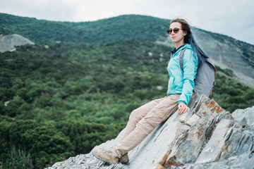 Naklejka na ściany i meble Hiker girl resting on rocks