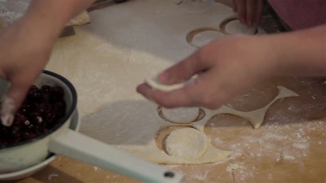 making dumplings of dough/Woman hands sculpt dough Pierogi with cherries