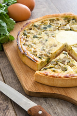 French quiche with vegetables on a rustic wooden table

