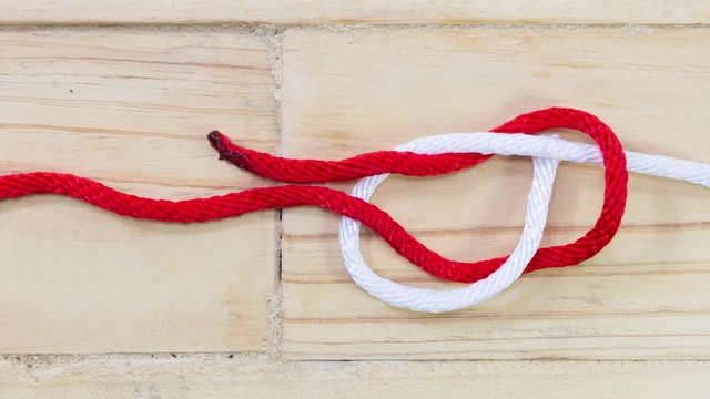 4k stop motion sheet bend knot made with red rope on wooden background.