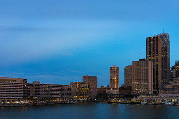 Cityscape at dusk, blue hour. Circular Quay skyscrapers and hotels with ferries in the bay in the evening. Sydney, Australia