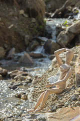 Wooden doll with the outline of a person sitting by the river, a