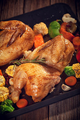 Roasted chicken with vegetables on baking plate