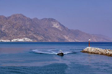 Powerboat the breakwater with a lighthouse in the harbor on the island of Kos.