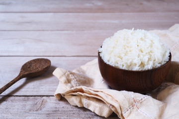 Close up of a bowl of cooked jasmine rice on a wooden table. 