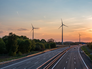 sunset over a highway, wind turbines in the background