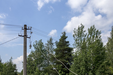 electric pole on the background of trees and blue sky with clouds