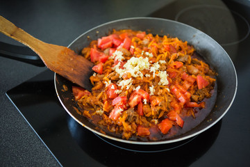 Woman fry the onion, carrots and garlic in a pan. Preparation for Lagman soup, borscht, saltwort. Homemade food.