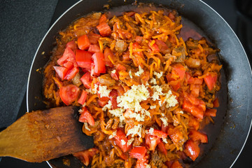 Woman fry the onion, carrots and garlic in a pan. Preparation for Lagman soup, borscht, saltwort. Homemade food.