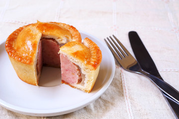 Close up of sliced traditional English pork pie on a white plate.