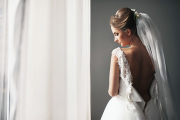 The bride stands near window