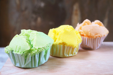 Close up of colorful steamed cup cakes on a wooden table.