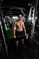 Fototapeta na wymiar Bodybuilder Performing Back Exercising With Barbell In Gym