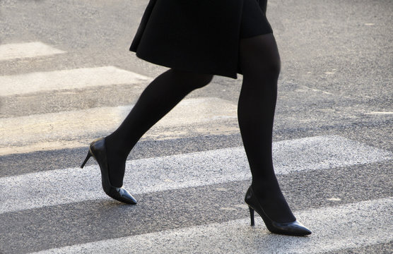 gambe di donna che attraversa le sulle strisce pedonali