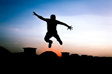 Defocused Silhouette of a boy is jumping over beautiful sunset background.