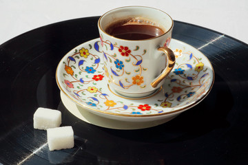 Nive day with music concept. Old vinyl plate and cup of coffee with sugar.