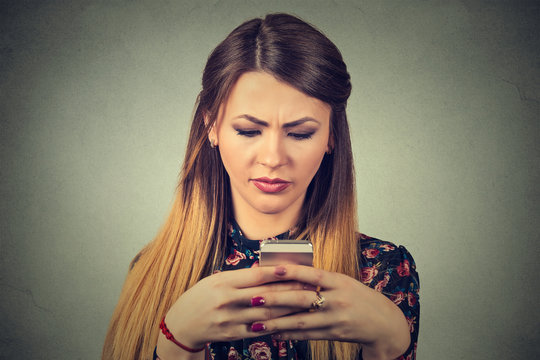 Upset unhappy woman holding cellphone. Sad looking girl texting on smartphone
