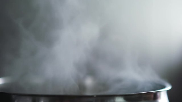 steam rising from pot with boiling water on kitchen slow motion