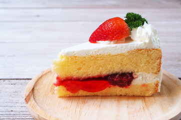 Close up of strawberry milk cake on a wooden plate.